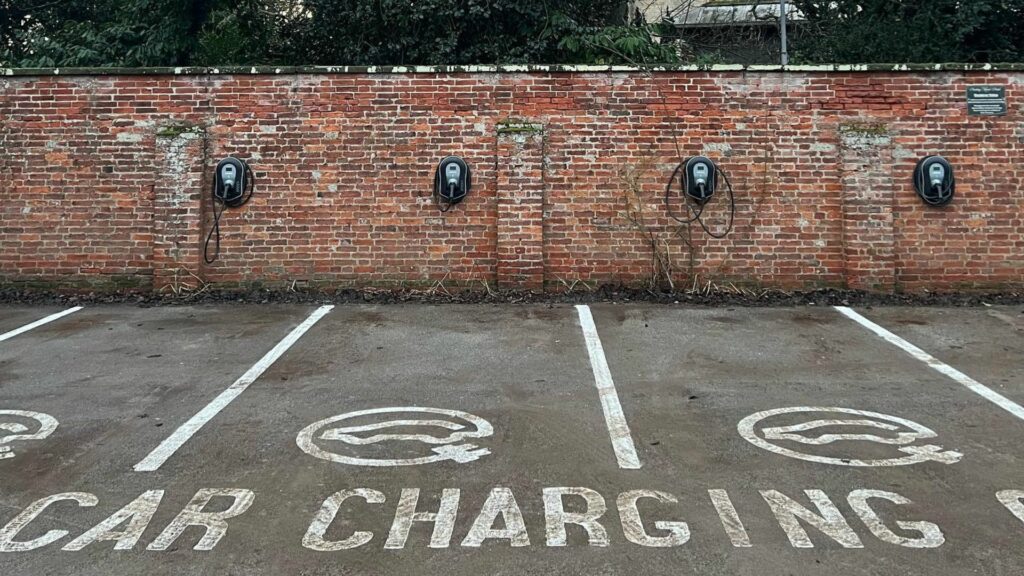 4 electric vehicle charge points on a red brick wall in the marked bay car park at Healing Manor