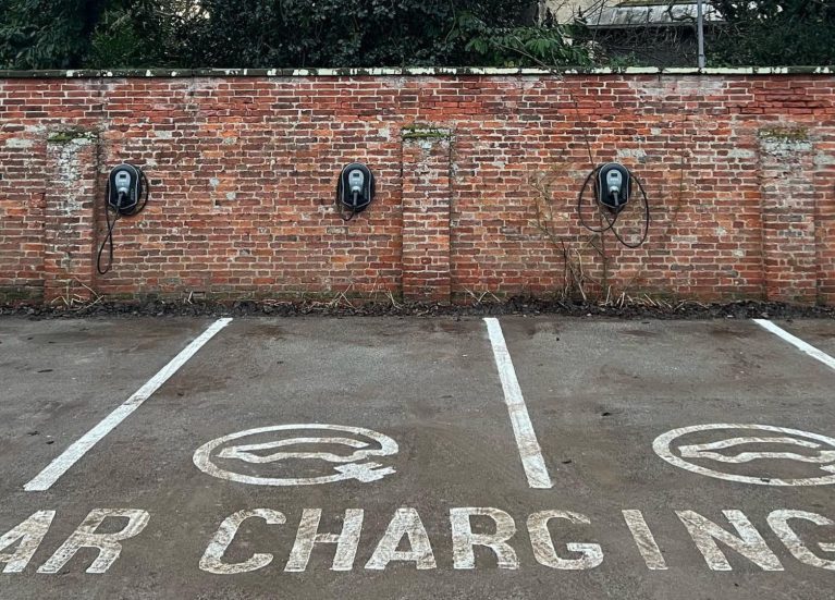 4 electric vehicle charge points on a red brick wall in the marked bay car park at Healing Manor